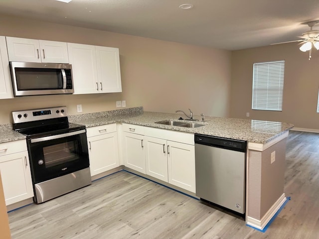 kitchen with stainless steel appliances, sink, white cabinets, and kitchen peninsula