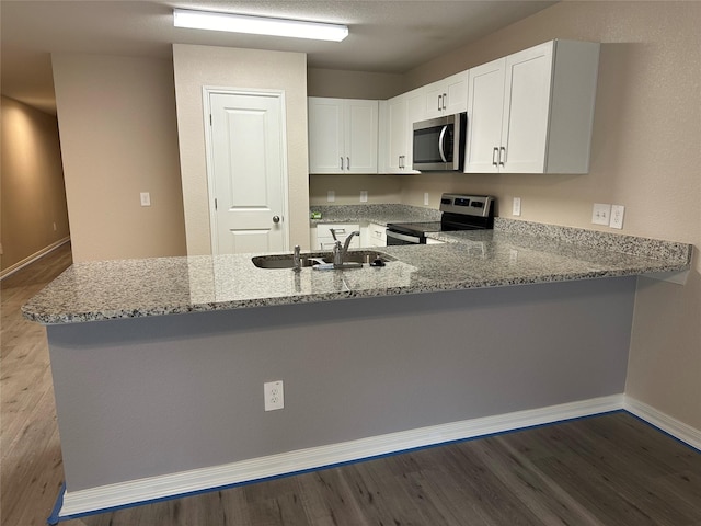 kitchen featuring white cabinetry, light stone counters, kitchen peninsula, and appliances with stainless steel finishes