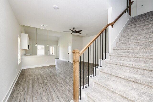 stairs with hardwood / wood-style flooring, ceiling fan, and vaulted ceiling