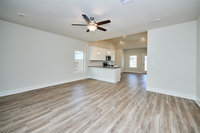 unfurnished living room featuring vaulted ceiling, light hardwood / wood-style flooring, and ceiling fan