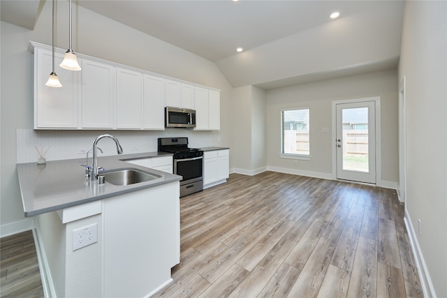 kitchen featuring pendant lighting, white cabinets, sink, appliances with stainless steel finishes, and kitchen peninsula