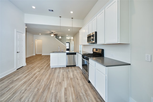 kitchen featuring white cabinets, sink, decorative light fixtures, kitchen peninsula, and stainless steel appliances