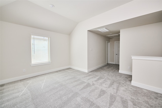 spare room with light colored carpet and lofted ceiling