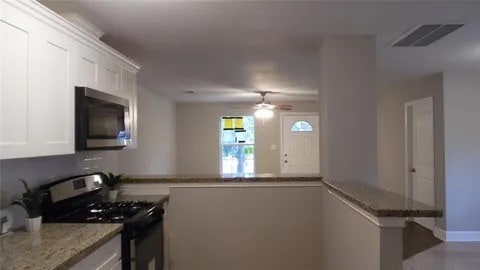 kitchen with white cabinetry, black range, kitchen peninsula, ceiling fan, and light stone countertops