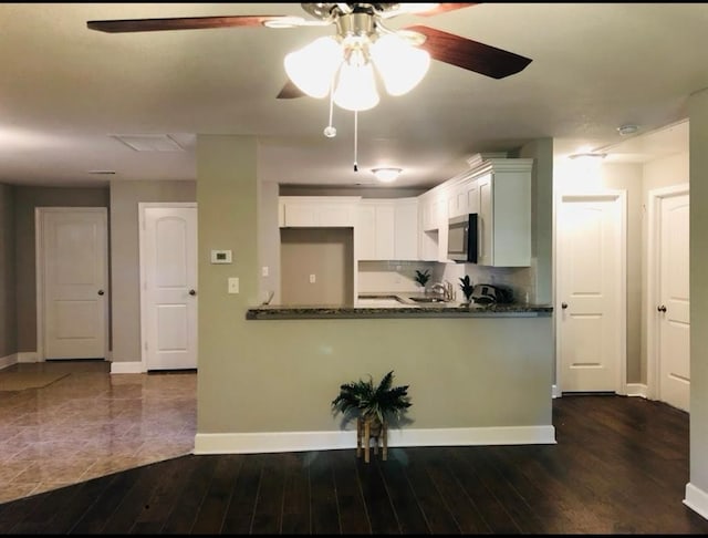 kitchen with dark stone countertops, dark wood-type flooring, ceiling fan, and white cabinets