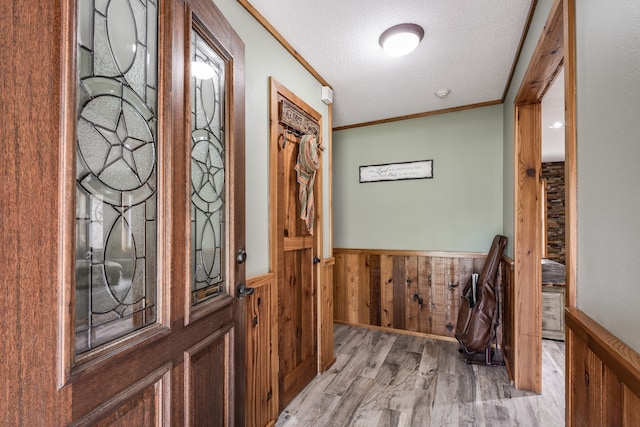 interior space with hardwood / wood-style flooring, wood walls, ornamental molding, and a textured ceiling