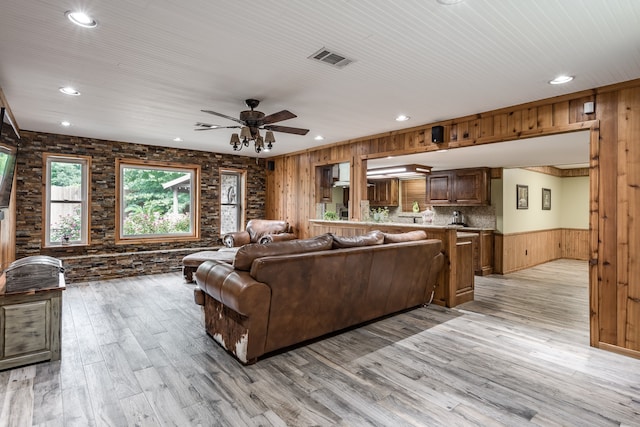 living room featuring light hardwood / wood-style floors, ceiling fan, and wooden walls