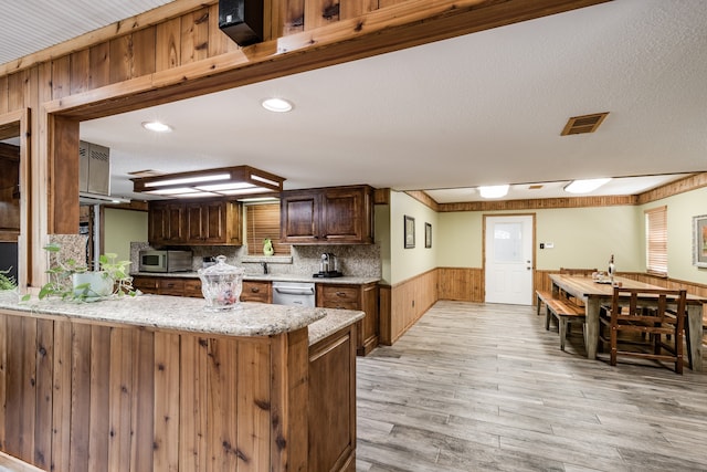 kitchen with light hardwood / wood-style floors, tasteful backsplash, light stone counters, and stainless steel appliances