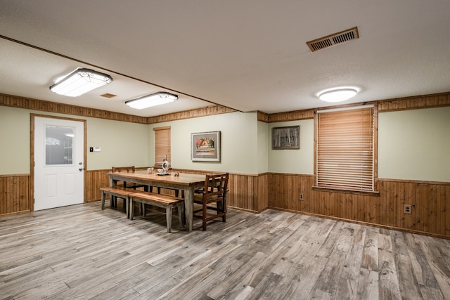 dining room featuring wooden walls, hardwood / wood-style floors, and a textured ceiling