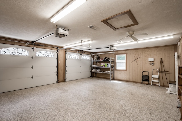 garage with a garage door opener, wood walls, and ceiling fan