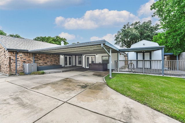 view of front of property featuring french doors, brick siding, a hot tub, central AC, and a front lawn