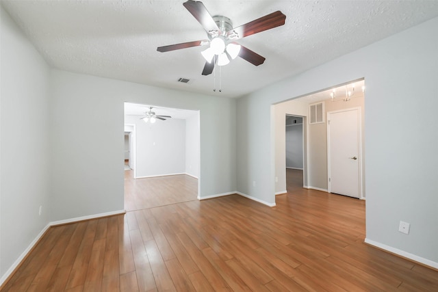 unfurnished room featuring baseboards, a textured ceiling, visible vents, and wood finished floors