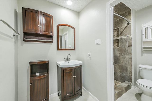 full bath featuring a textured ceiling, vanity, a tile shower, and toilet