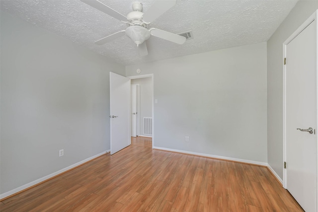 spare room featuring baseboards, visible vents, and wood finished floors