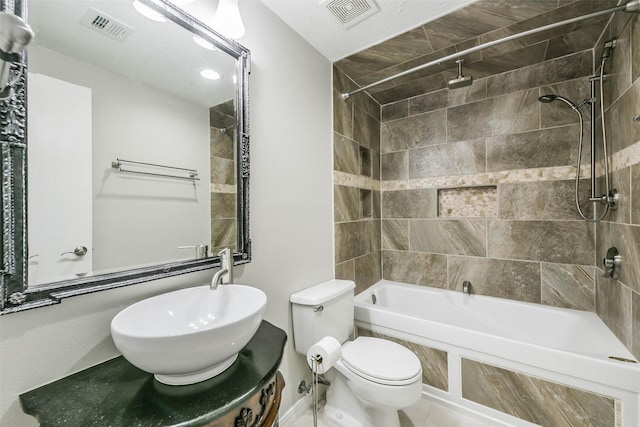 bathroom with toilet, visible vents, tiled shower / bath combo, and a sink