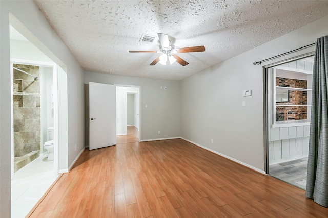 unfurnished room with baseboards, visible vents, ceiling fan, wood finished floors, and a textured ceiling