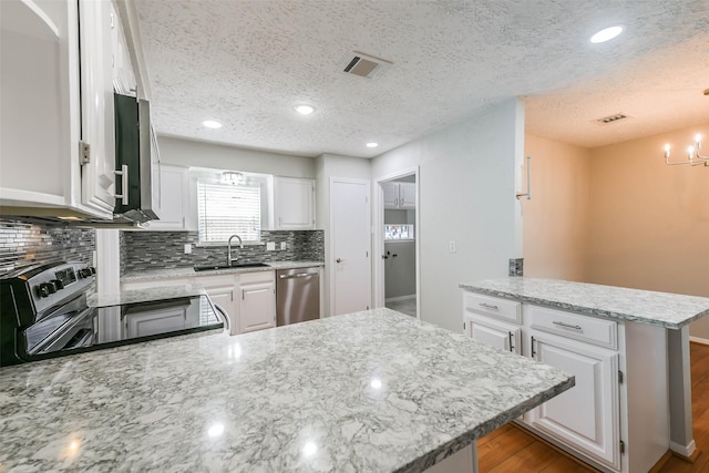 kitchen featuring stainless steel appliances, visible vents, white cabinetry, a sink, and a peninsula