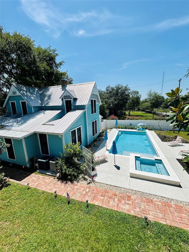 view of pool with an in ground hot tub, a patio, and a lawn