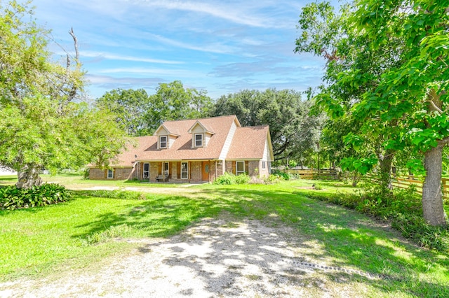 cape cod house featuring brick siding, driveway, and a front yard