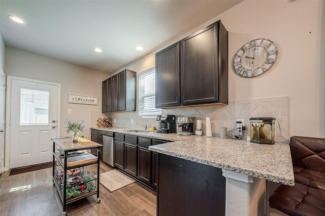 kitchen with light wood-type flooring, backsplash, a wealth of natural light, a breakfast bar, and dark brown cabinets