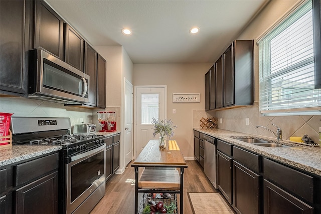 kitchen with light stone counters, light hardwood / wood-style floors, decorative backsplash, dark brown cabinets, and appliances with stainless steel finishes