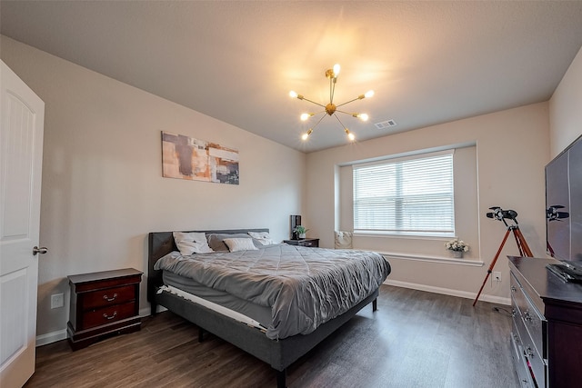 bedroom with dark hardwood / wood-style floors and an inviting chandelier