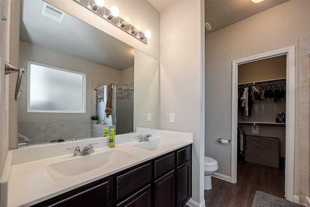 bathroom featuring hardwood / wood-style floors, vanity, toilet, a textured ceiling, and an enclosed shower