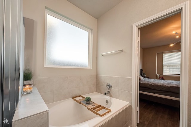 bathroom featuring wood-type flooring and tiled tub