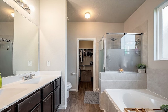 full bathroom featuring vanity, a textured ceiling, hardwood / wood-style floors, shower with separate bathtub, and toilet