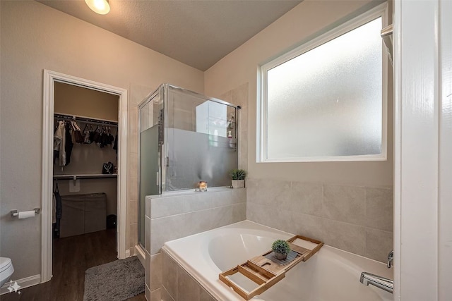 bathroom featuring hardwood / wood-style flooring, a textured ceiling, and plus walk in shower