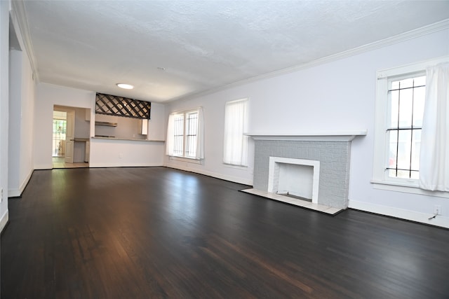 unfurnished living room with dark hardwood / wood-style floors, a brick fireplace, ornamental molding, and a textured ceiling