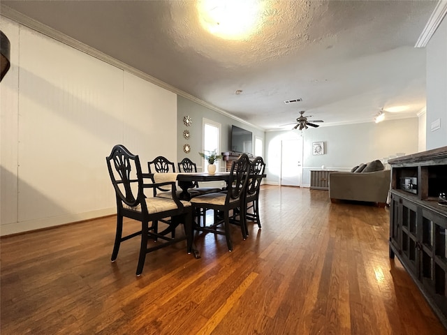 dining room with dark hardwood / wood-style floors, ceiling fan, ornamental molding, and a textured ceiling