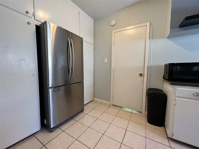 kitchen with white cabinetry, stainless steel fridge, and light tile patterned floors