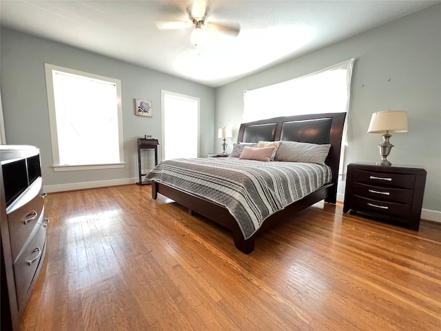 bedroom featuring multiple windows, hardwood / wood-style flooring, and ceiling fan