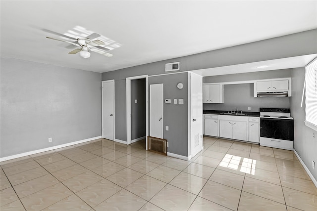 kitchen featuring sink, light tile patterned floors, electric range, white cabinetry, and ceiling fan