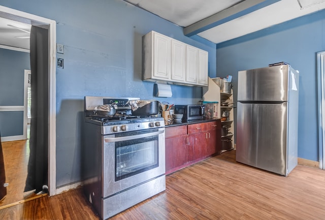 kitchen with appliances with stainless steel finishes, light hardwood / wood-style flooring, beam ceiling, and white cabinetry