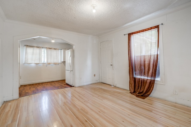 empty room featuring light hardwood / wood-style floors, a textured ceiling, and crown molding