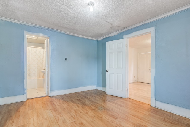 unfurnished bedroom featuring ensuite bathroom, crown molding, light wood-type flooring, and a textured ceiling