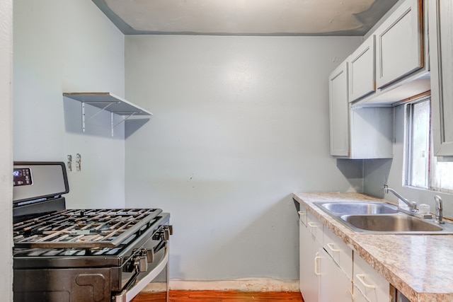 kitchen featuring light hardwood / wood-style floors, sink, white cabinetry, and stainless steel gas range oven