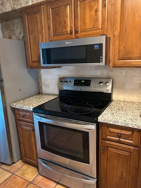 kitchen featuring light stone countertops, decorative backsplash, and appliances with stainless steel finishes