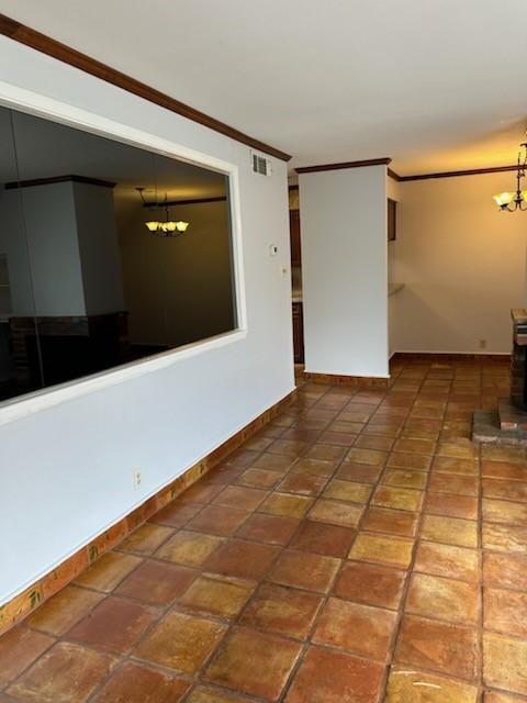 unfurnished room with crown molding and a chandelier