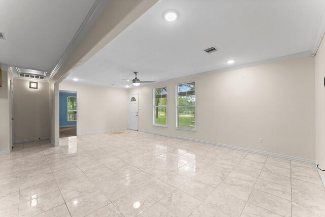 empty room featuring ceiling fan, ornamental molding, and a wealth of natural light