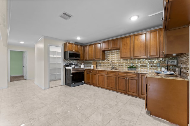 kitchen with light stone countertops, stainless steel appliances, sink, and decorative backsplash