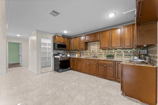 kitchen featuring visible vents, decorative backsplash, brown cabinets, stainless steel appliances, and a sink