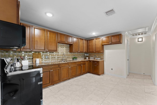 kitchen with visible vents, brown cabinets, a sink, black microwave, and backsplash