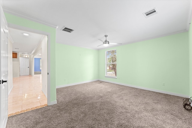 empty room featuring ceiling fan, visible vents, crown molding, and light colored carpet