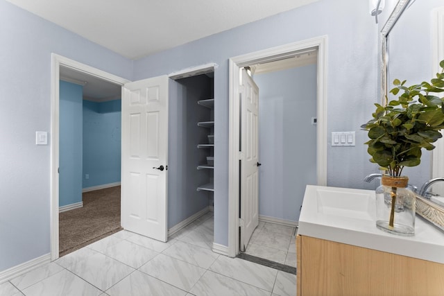 bathroom with marble finish floor, vanity, and baseboards