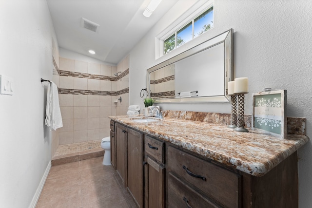 bathroom with vaulted ceiling, vanity, a tile shower, toilet, and tile patterned floors