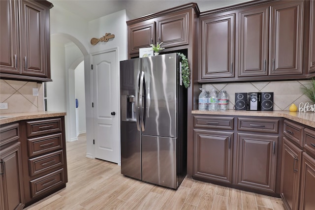 kitchen featuring light hardwood / wood-style floors, dark brown cabinetry, decorative backsplash, and stainless steel fridge with ice dispenser