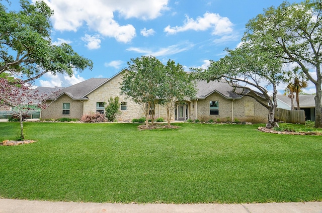 view of front of home featuring a front yard, fence, and stone siding